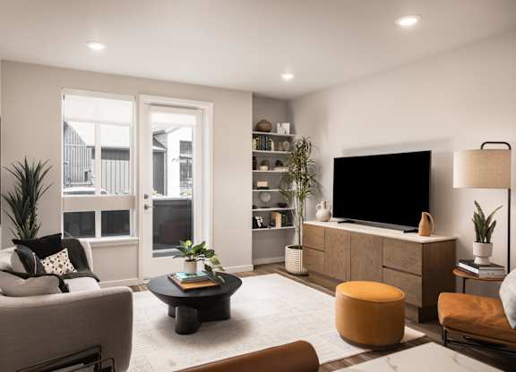 A modern living room with a grey sofa, a black coffee table, a wooden cabinet, and a flat-screen TV.