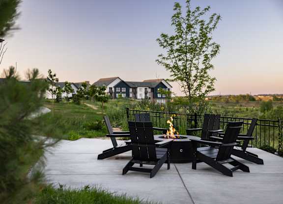 A patio with chairs and a fire pit in the middle.