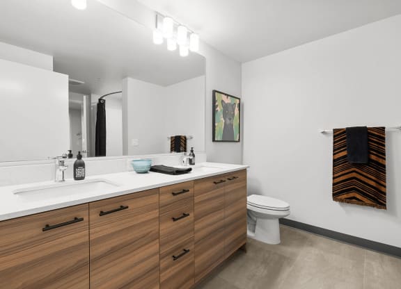 a bathroom with white walls and a wooden vanity with two sinks and a toilet at Ion Town Center, Shoreline, WA 98133