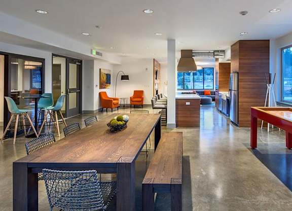 Communal lounge with dining table and orange accent chairs at Six Oaks Apartments, Bothell, WA 98011