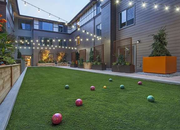 Courtyard with artificial turf and colorful bocce balls at Six Oaks Apartments, Bothell, Washington
