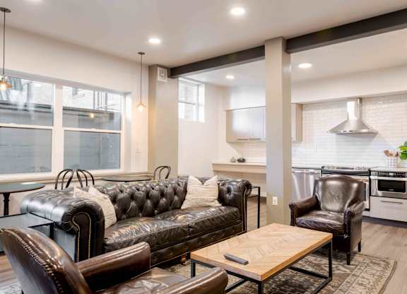 A modern living room with a black leather couch and a wooden coffee table.