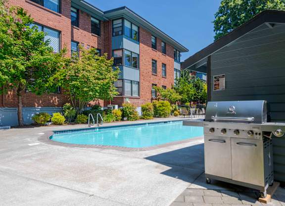 A barbecue grill is placed next to a small pool in a courtyard.