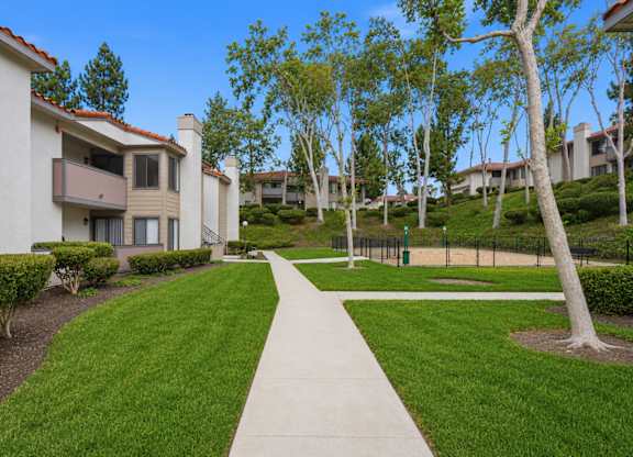 A pathway leads through a grassy area between two rows of houses.