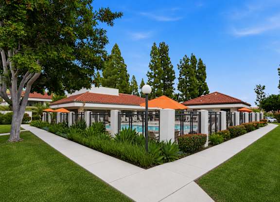 A building with orange awnings is surrounded by greenery and a clear blue sky.
