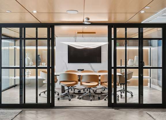 A conference room with a table and chairs is visible through a glass door.