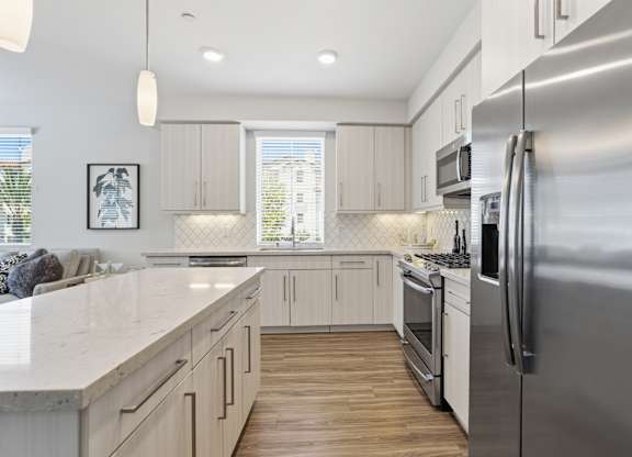 A modern kitchen with a stainless steel refrigerator and wooden floors.