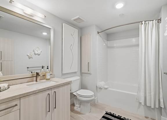 A white bathroom with a toilet, sink, and bathtub.