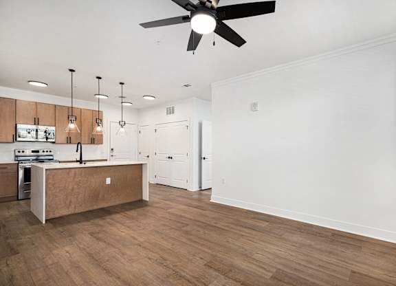 A kitchen with wooden floors and a ceiling fan.