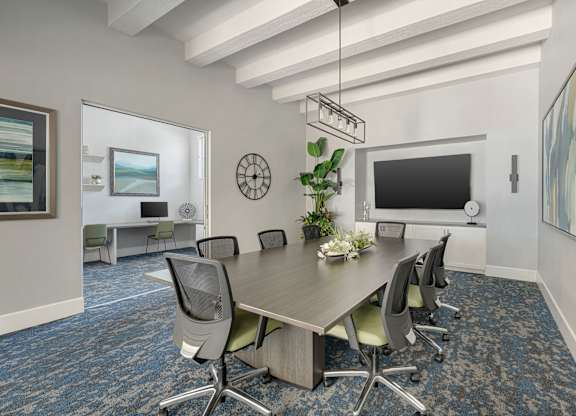 A conference room with a long table surrounded by chairs.
