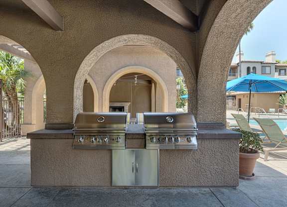 A barbecue grill is built into a wall with arches.