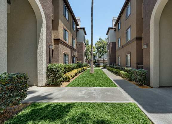 A long, narrow walkway separates two rows of apartment buildings.