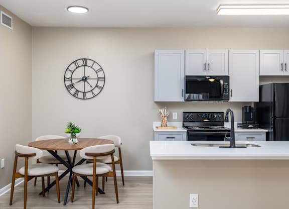 A kitchen with a table and chairs and a clock on the wall at Clear Creek Meadows Apartments, Copperas Cove