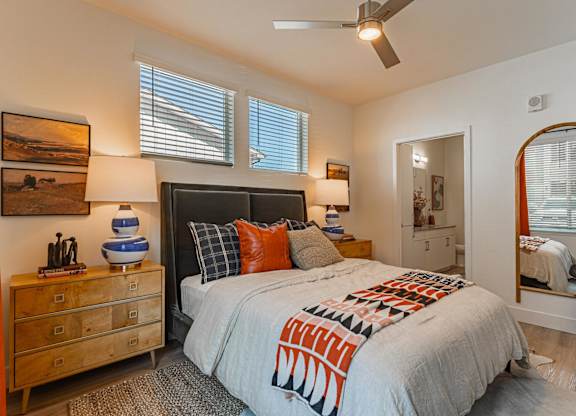 A bedroom with a bed, dresser, and mirror at Firestone Junction apartments for rent in Northern Colorado.