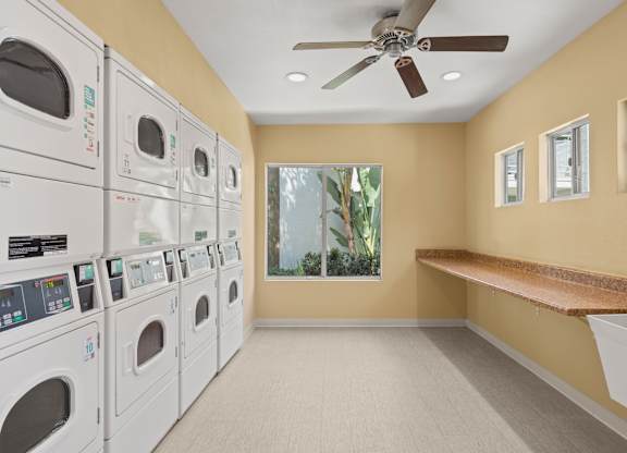 A laundry room with a row of washers and dryers.