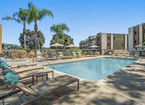 A resort style pool with lounge chairs and umbrellas.
