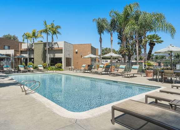 A resort style pool with lounge chairs and umbrellas.