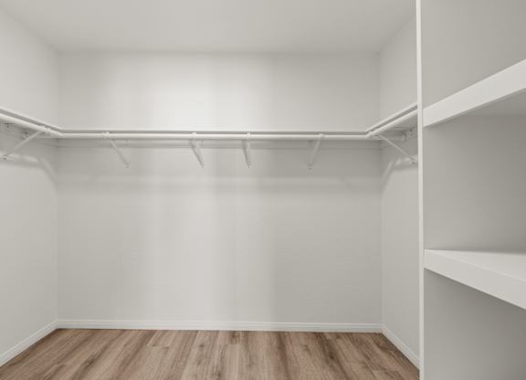 A spacious closet with hardwood floors and shelving.