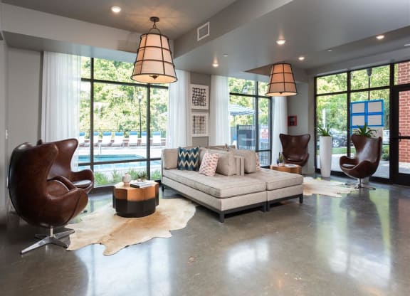a living room with a couch and chairs and large windows