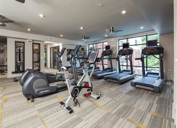 a gym with cardio equipment and windows in a building