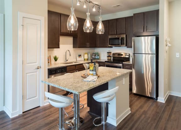 a kitchen with an island and stainless steel refrigerator