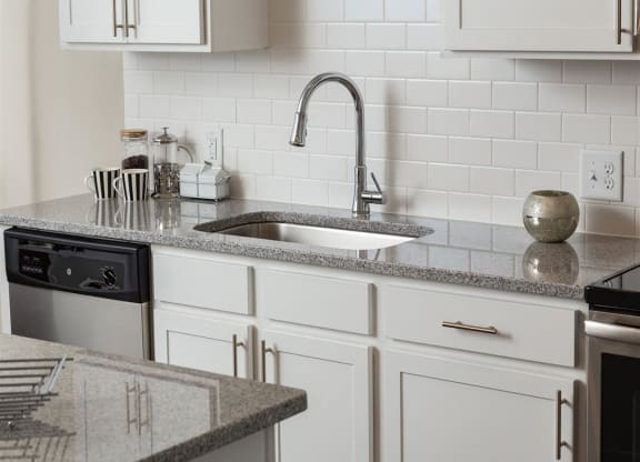 a white kitchen with granite counter tops and a sink