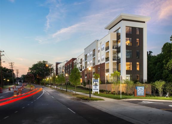 a rendering of an apartment building at dusk on a city street