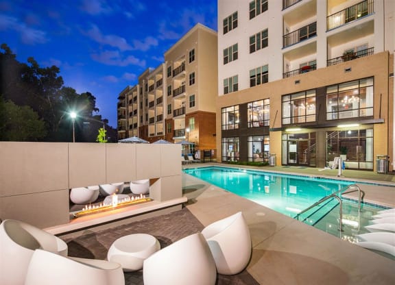a swimming pool with chairs and a fire pit at night