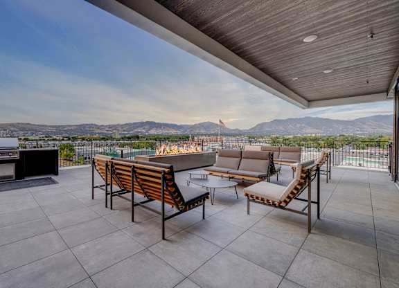 A patio with a table and chairs overlooking a mountain range.