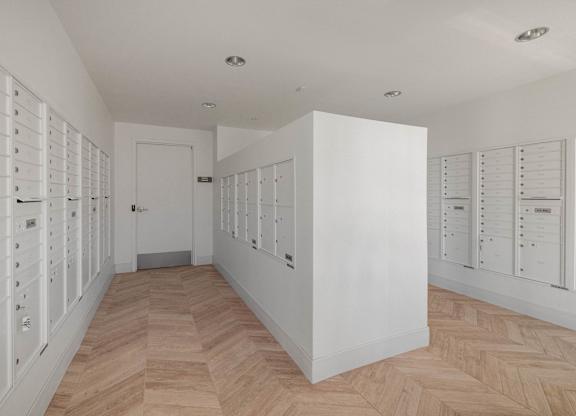 A hallway with a white wall and a wooden floor.
