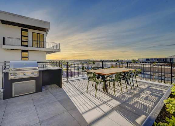A patio with a table and chairs and a grill.