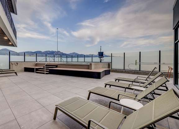 A rooftop patio with sun loungers and a view of the mountains.