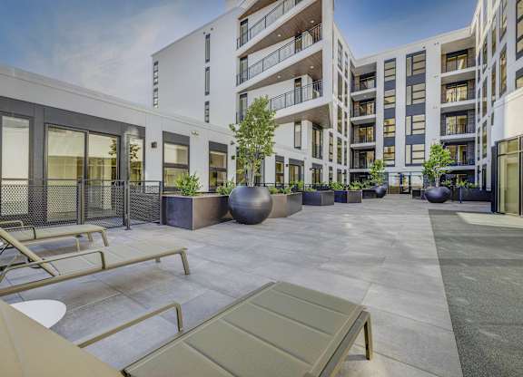 A modern courtyard with a bench and a tree in front of apartment buildings.