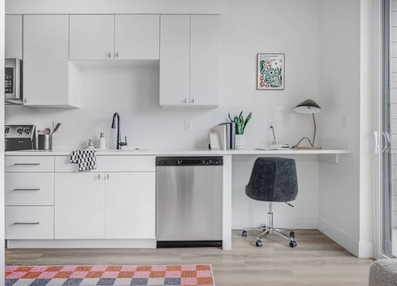 A kitchen with white cabinets and a black chair.