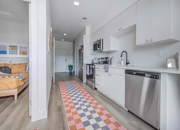 A kitchen with a checkered rug on the floor.