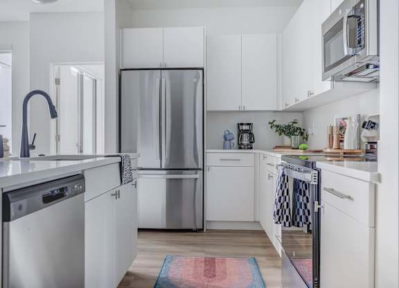 A modern kitchen with white cabinets and stainless steel appliances.