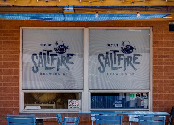 Saltfire Brewing Co. logo on a window with blue chairs outside.
