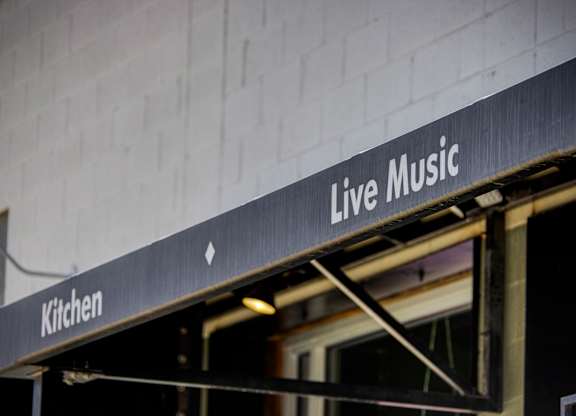 A sign that says Live Music is hanging from the side of a building.
