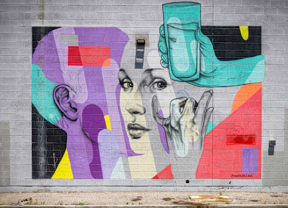 A colorful mural of a woman's face with a vase on her head.