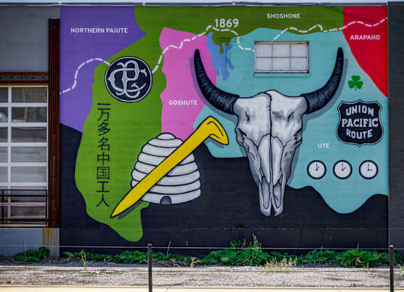 A mural on a wall with a skull and a pencil in the center.