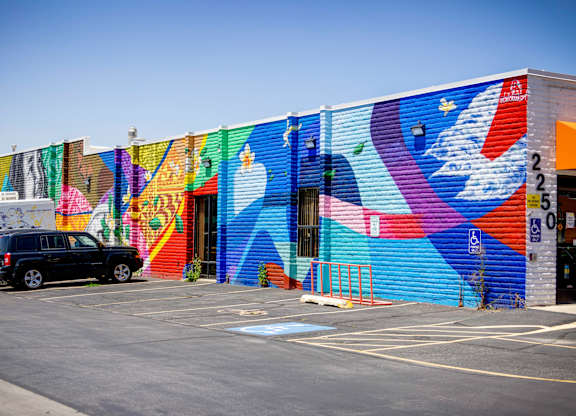 A colorful mural on a building with a car parked in front.