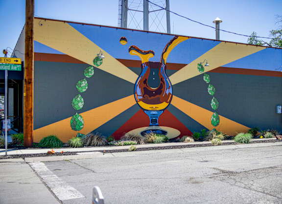 A mural of a bird with green leaves around its neck is painted on a wall.