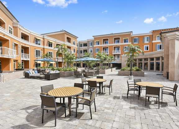 A courtyard with tables and chairs surrounded by buildings.