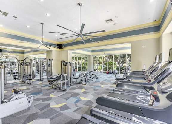 A gym with treadmills, elliptical machines, and a fan.