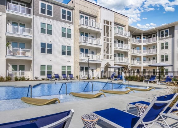 an apartment building with a swimming pool and lounge chairs