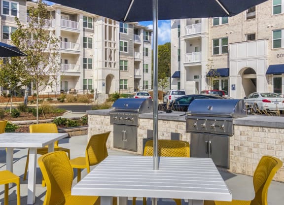 a patio with tables and chairs and two barbecue grills