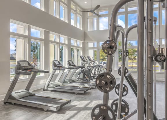 a gym with cardio equipment and windows in a building