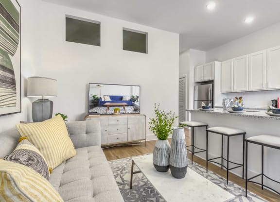 a living room with a couch and a kitchen with stools