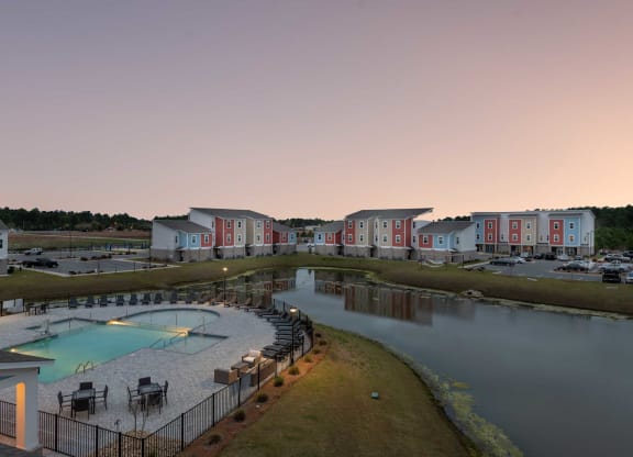 a building with a pool and a lake at dusk