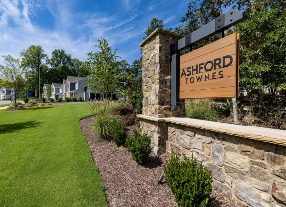 a sign for ashford towers on the side of a stone wall with a lawn
